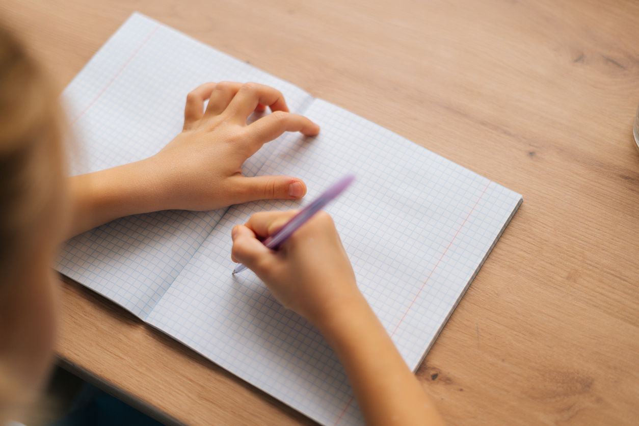 hands holding a pen and writing on a paper