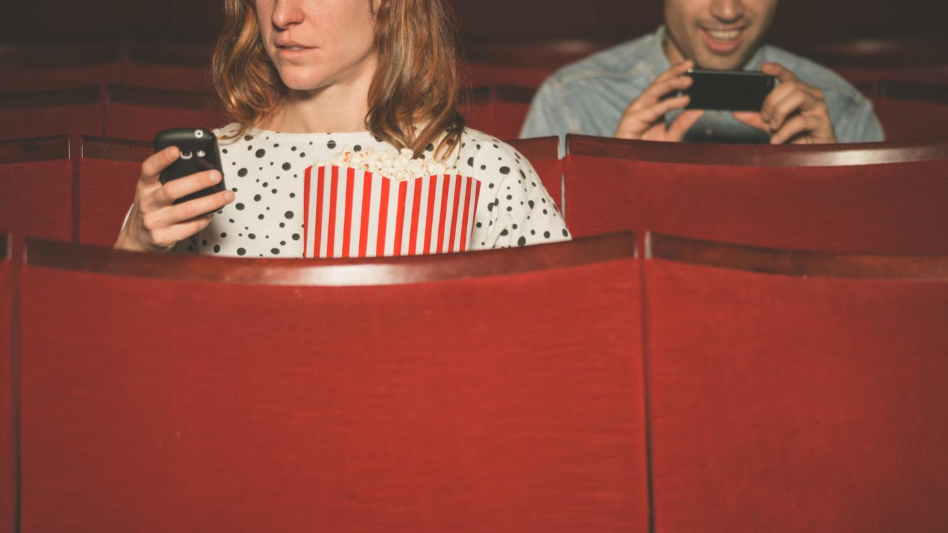 People on their phones in a movie theater