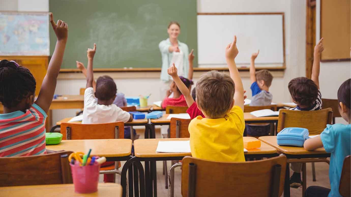 students raising hands in a classroom