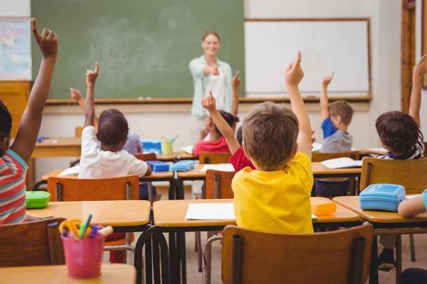 students raising hands in a classroom