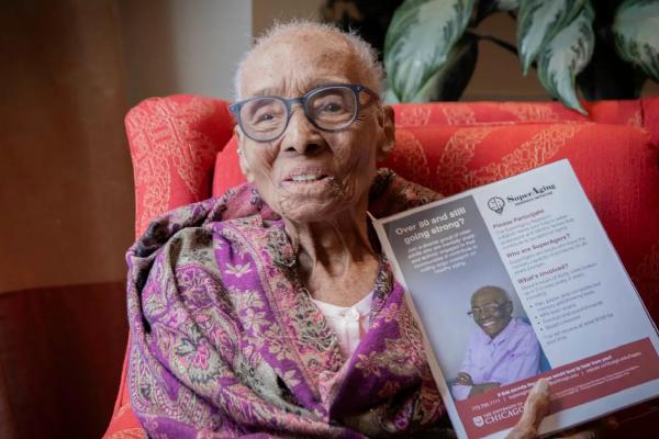 SuperAger Edith Renfrow Smith, 110, holds a flyer for the SuperAging Research Initiative that features a photo of her. Photo by Chris Jones